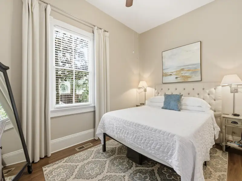 Queen bedroom in Suite 314A Savannah vacation rental — white bedding smart TV dresser hardwood floors natural light