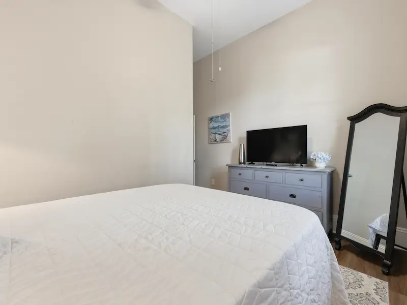Suite 314A queen bedroom historic Savannah vacation suite — floating TV shelf natural light curtains